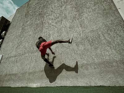 Shadow of an athlete performing a dynamic movement on wall